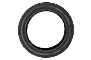 EMMO 120/80-16 motorcycle-style ebike tire displayed on rugged ground, showing its solid pattern blocks and water-dispersing channels ideal for city commute and trail exploration