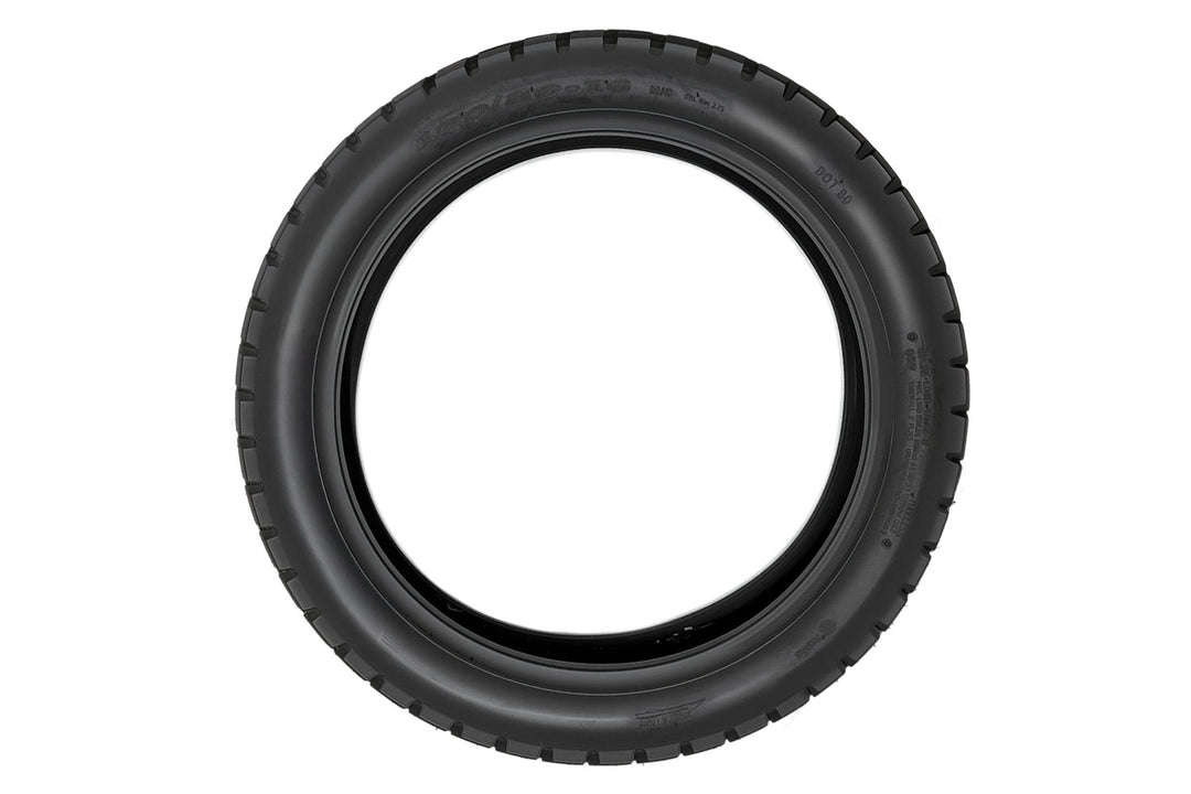EMMO 120/80-16 motorcycle-style ebike tire displayed on rugged ground, showing its solid pattern blocks and water-dispersing channels ideal for city commute and trail exploration