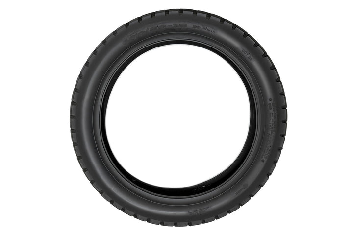 EMMO 120/80-16 motorcycle-style ebike tire displayed on rugged ground, showing its solid pattern blocks and water-dispersing channels ideal for city commute and trail exploration